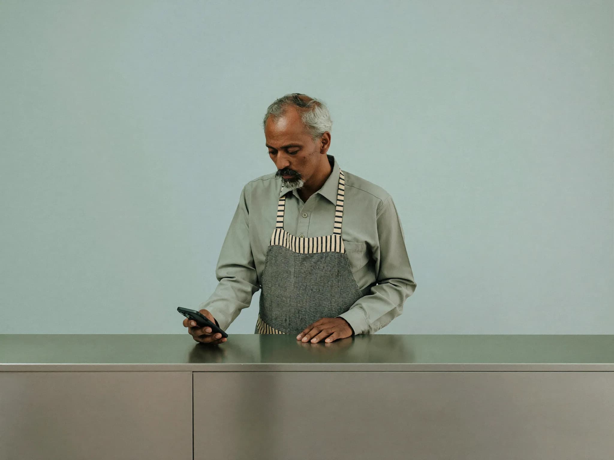 A shopkeeper at his counter, looking at his phone